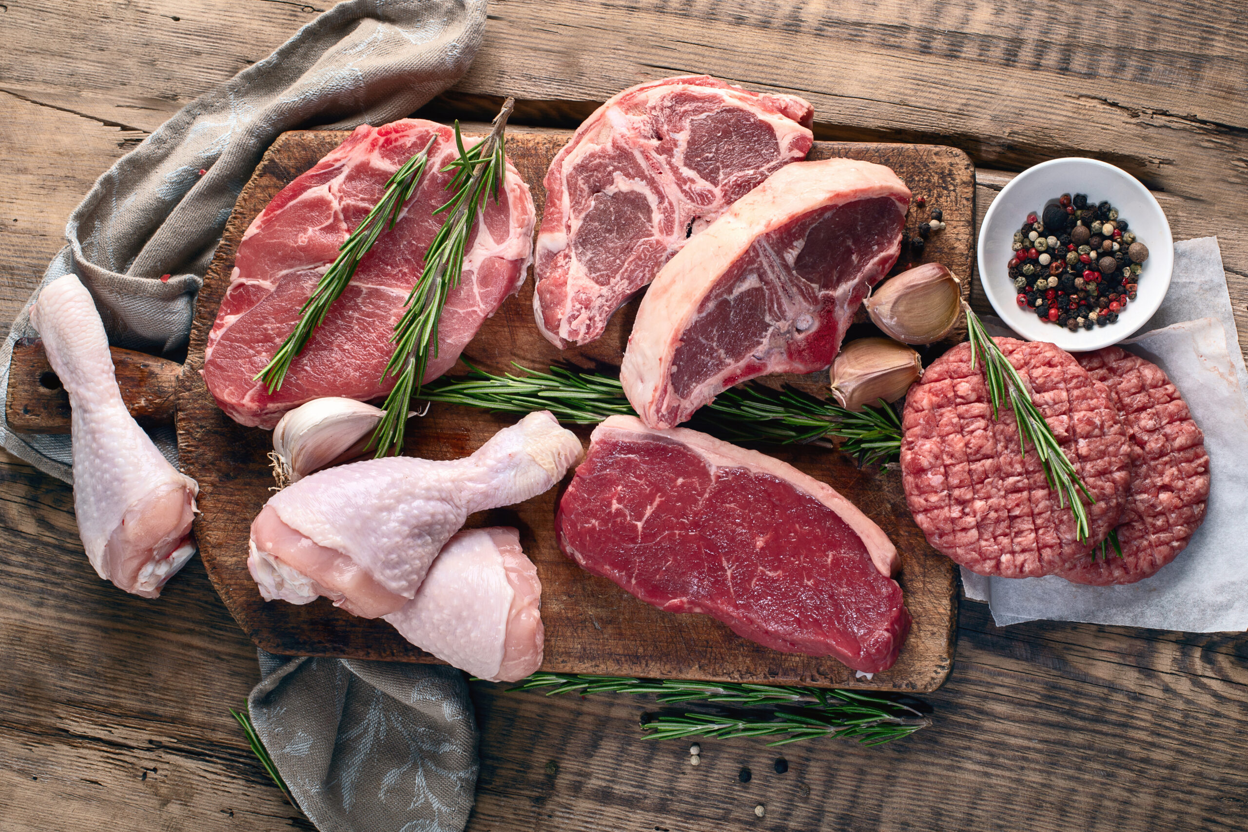 Different types of raw meat Person holding a glass milk bottle tied with twine, wearing a plaid shirt, with a blurred green garden background. Ideal for topics on homemade dairy, sustainability, or organic farming.